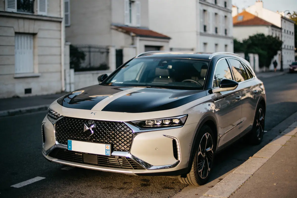 SUV gris stationné sur une rue résidentielle, bâtiments en arrière-plan, éclairage de soirée.