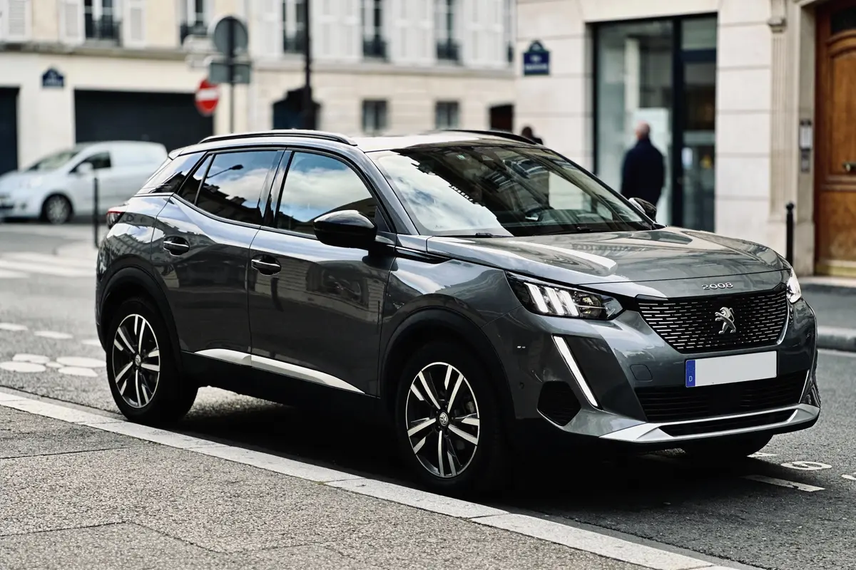 SUV gris Peugeot 2008 stationné dans une rue urbaine, arrière-plan avec bâtiments résidentiels.