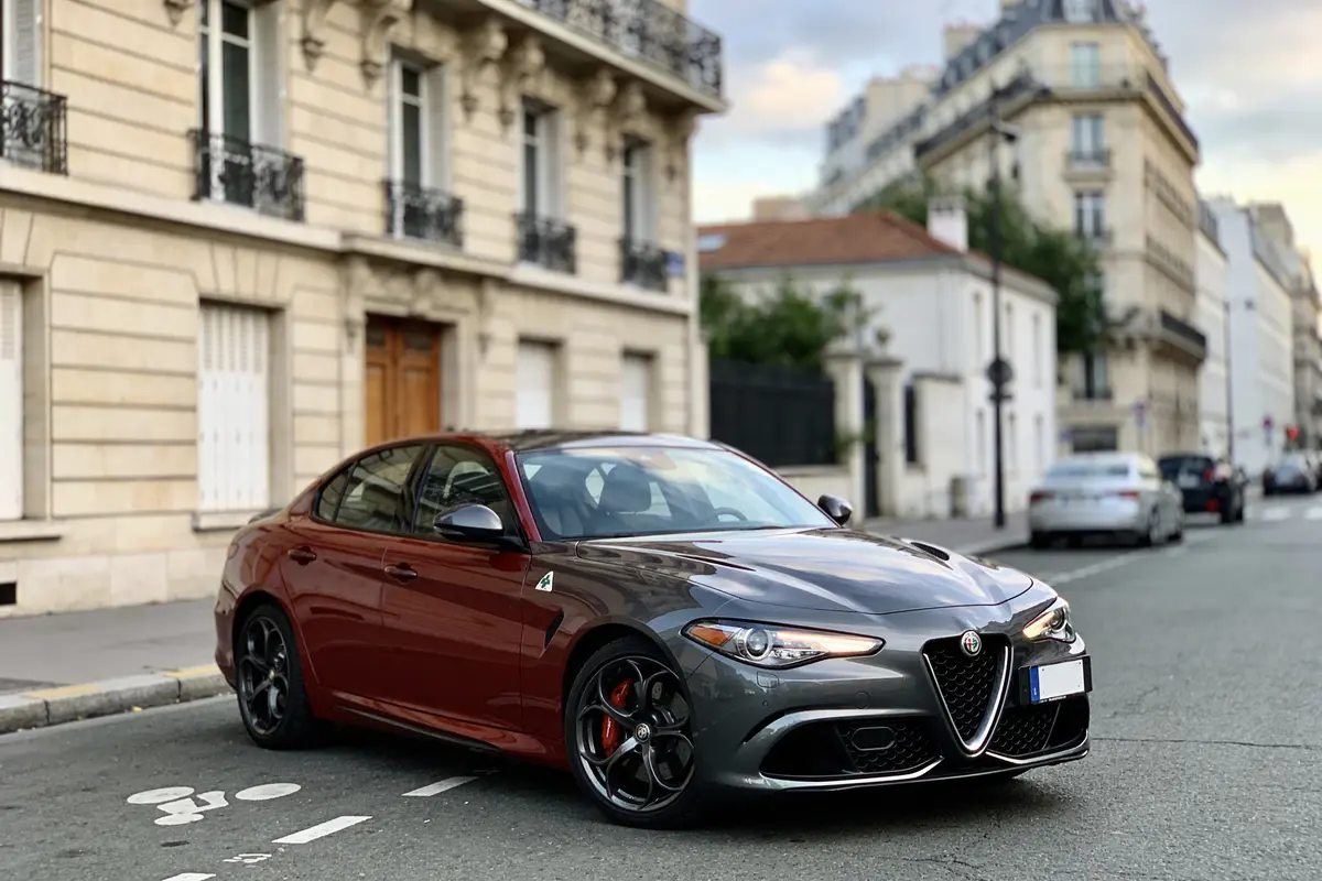 Voiture Alfa Romeo grise garée dans une rue parisienne résidentielle, immeubles en arrière-plan.