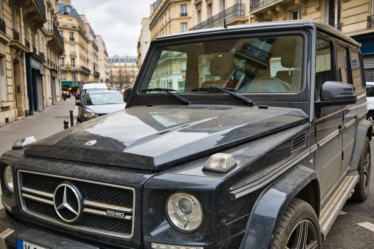 SUV noir garé dans une rue parisienne bordée d'immeubles haussmanniens.