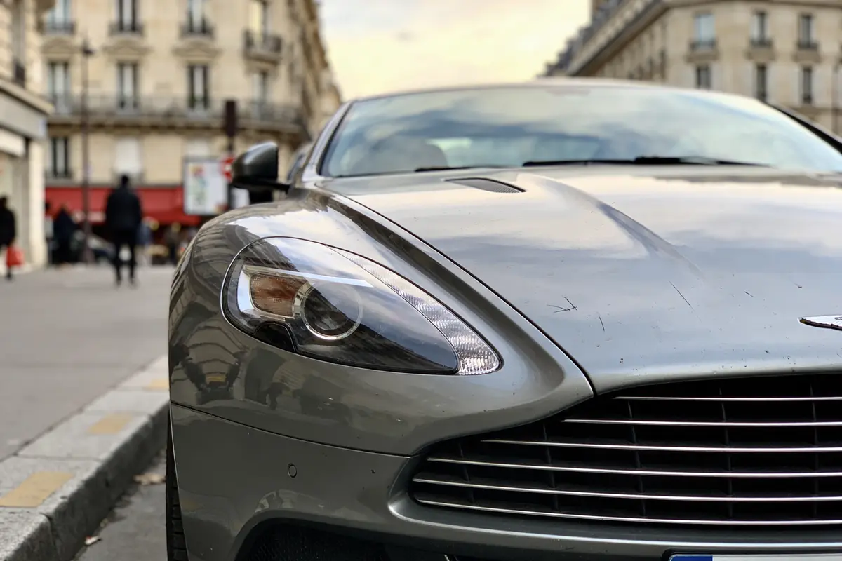 Voiture de luxe argentée stationnée en ville, immeubles anciens en arrière-plan.