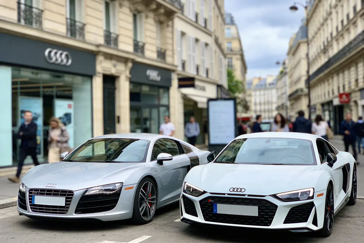 Deux voitures Audi sport stationnées devant un magasin dans une rue animée de la ville.