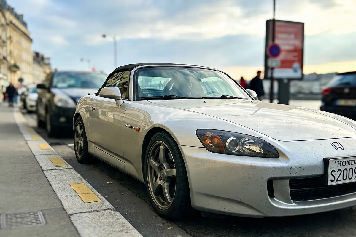Voiture de sport Honda blanche garée en ville, sous un ciel partiellement nuageux.