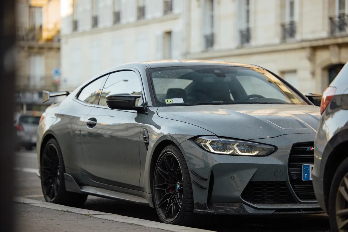 Voiture de sport grise stationnée dans une rue urbaine, vue de l'avant et du côté.