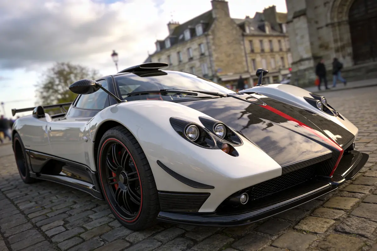 Voiture de sport blanche sur pavés, ciel nuageux en arrière-plan urbain.