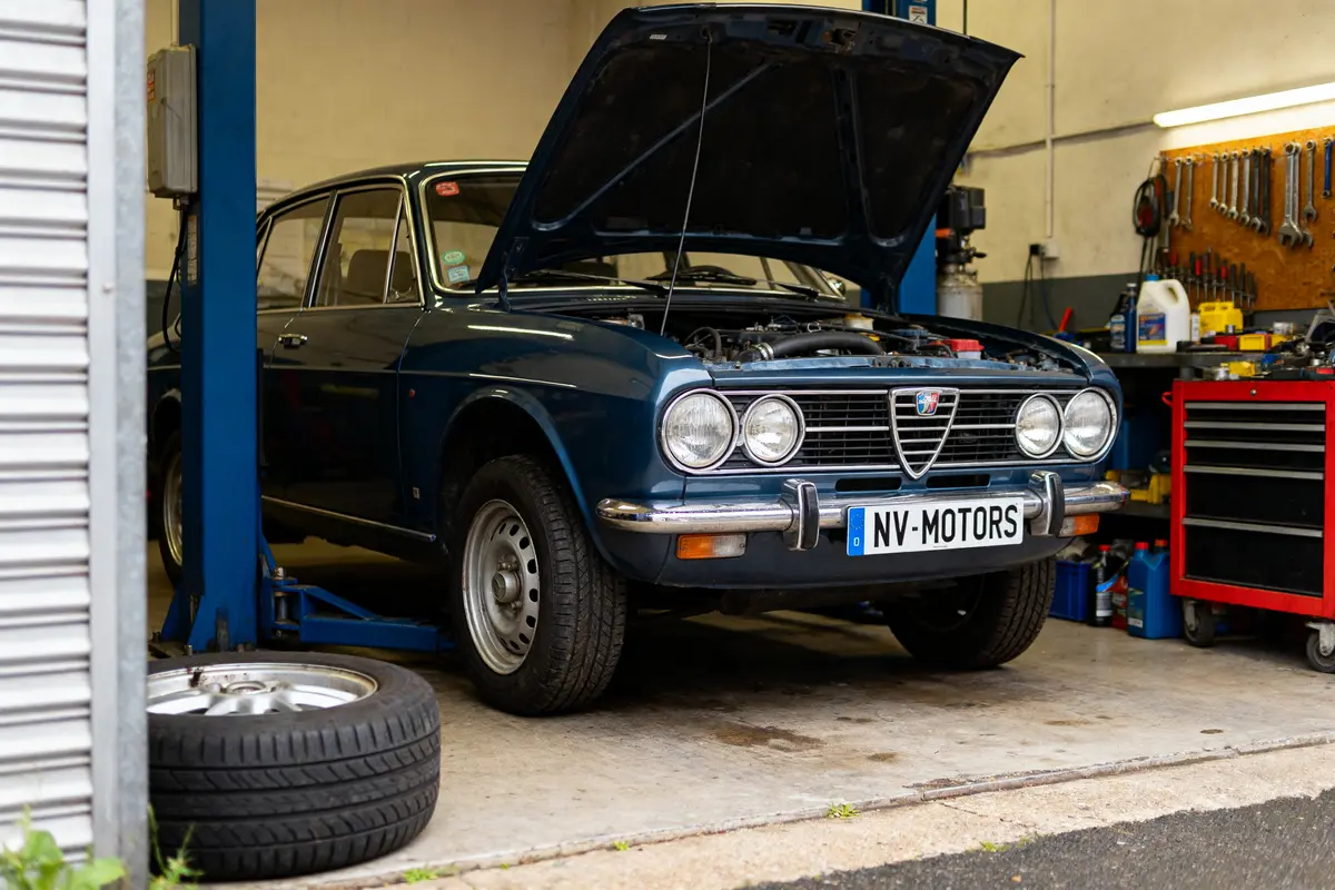Voiture classique en réparation chez MV Motors Nemours avec capot ouvert dans le garage