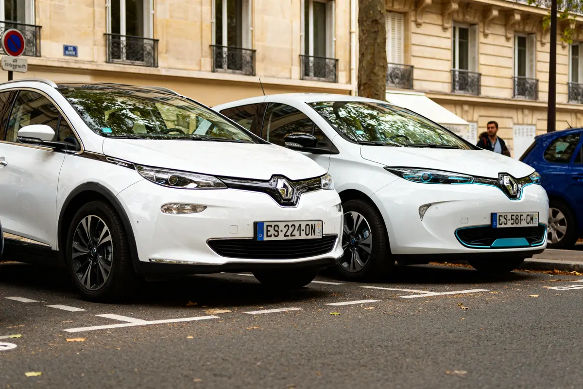 Deux voitures Renault blanches garées en ville pour choisir entre hybride et électrique