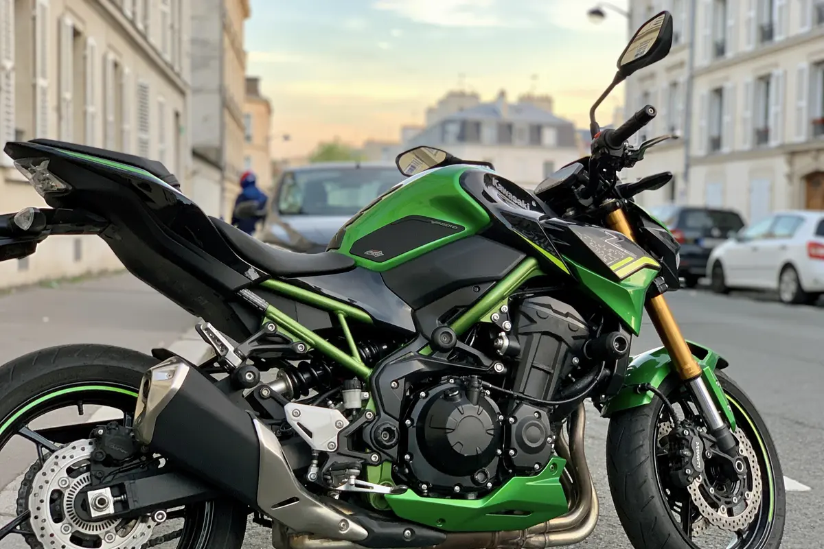 Moto verte garée dans une rue urbaine avec bâtiments en arrière-plan, perspective latérale droite.