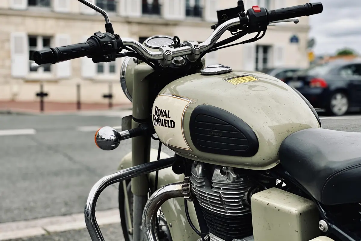 Gros plan d'une moto Royal Enfield garée dans une rue, avec guidon et réservoir visibles.